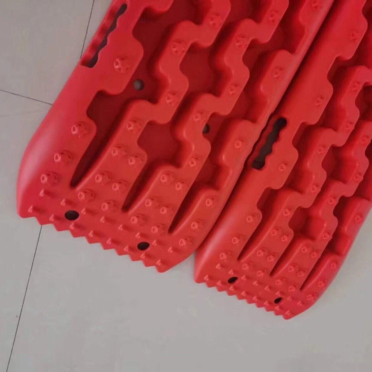 Close-up of red heavy duty traction boards with aggressive tread pattern