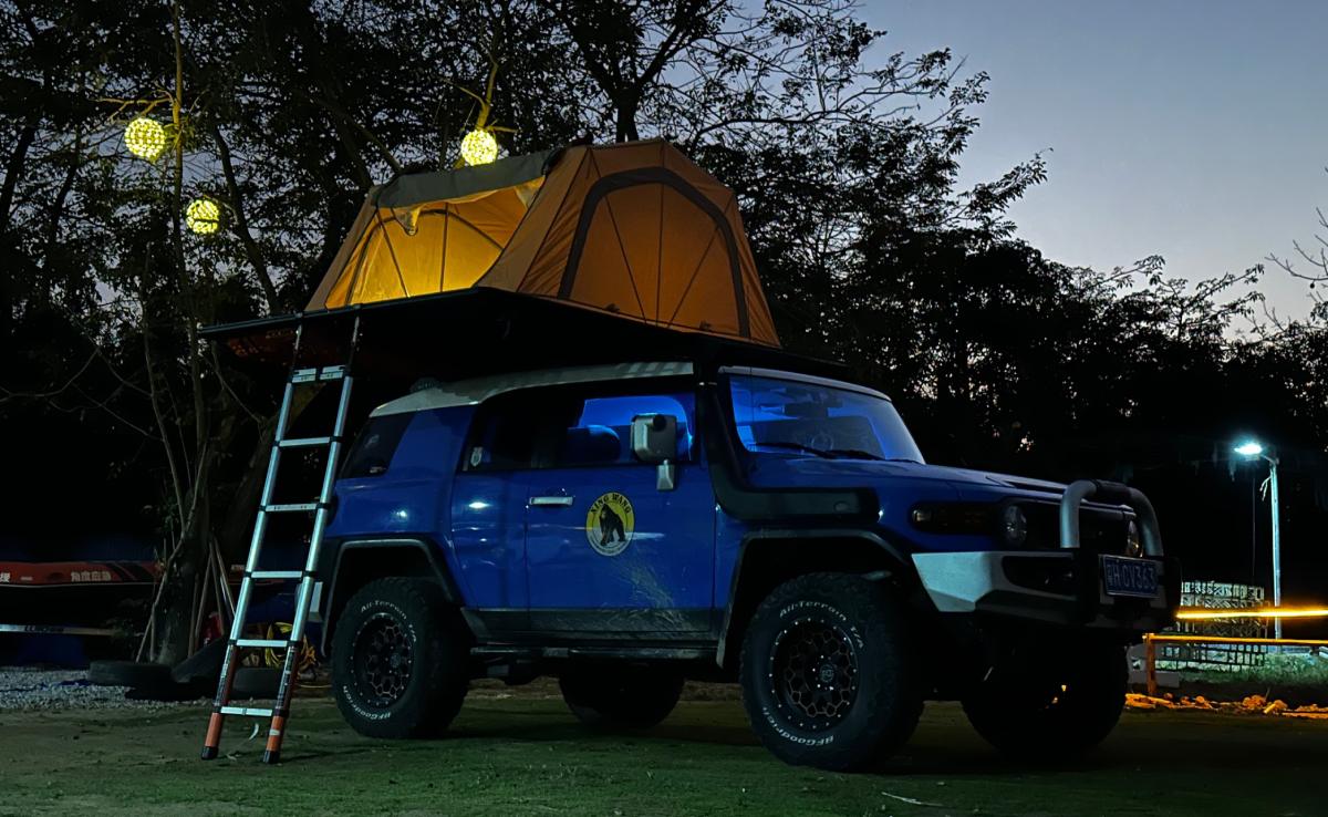 4WD with professional roof rack and rooftop tent at night, ladder attached