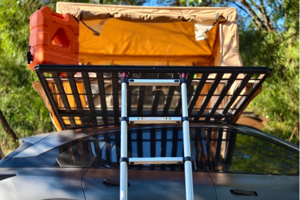 Car roof rack with mounted roof top tent and ladder for outdoor camping